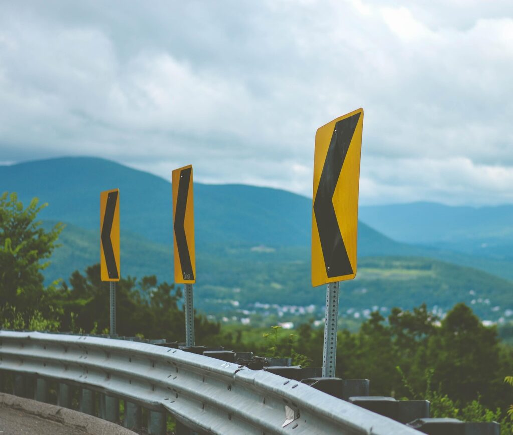 road sign, street sign, sharp curves, arrow, sign, road, traffic, warning, street, direction, corner sign, corner, guardrail, hairpin turn, turn, driving, yellow, guardrail, guardrail, guardrail, guardrail, guardrail